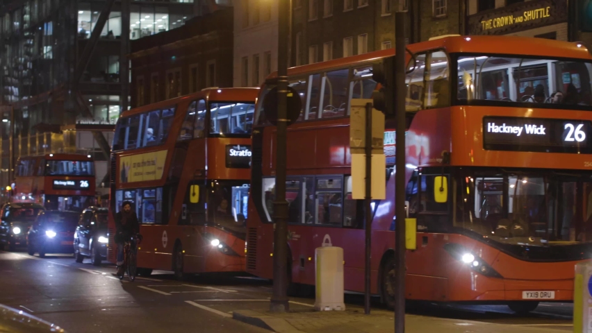 Red London buses moving on busy street of Shoreditch London in the evening. London 25 JAN 2022