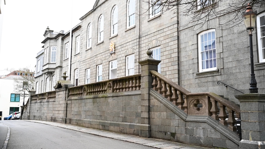 Old main entrance to Royal Court and States of Deliberation Chamber,Court Row, St Peter Port, Guernsey showing crest , building frontage and elevated stone steps to entrance