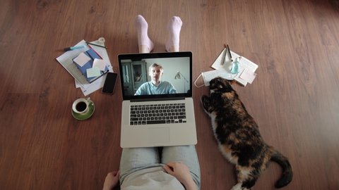 Young woman with cat pet smiling while videoconferencing at home during coronavirus self quarantine. Family video conversation via internet, couple on distance, home isolation lockdown closed boarders