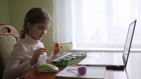 Distance Learning. Schoolgirl Studying Online Using Laptop Music Lesson. School Student Wearing Headphones Watching Internet Video Music Course. Caucasian Girl Learning to Play Xylophone, Piano.