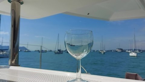 Phuket, Thailand, 19, December, 2020:
Pouring wine into a glass on board a sailboat, wine being poured from a bottle into a glass on a yacht