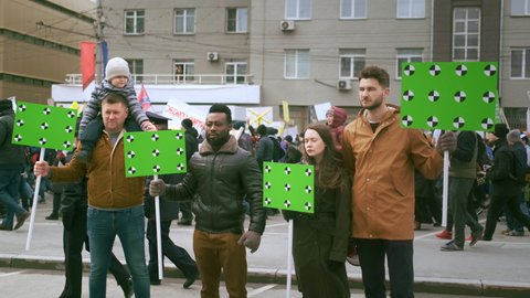 Russia, Novosibirsk - 01.05.2019: City event of Monstration. People participate in funny march with ridiculous banners. African and White men with empty green screen space, mock up chroma key placards