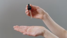 Asian Woman Holding an Eye Dropper Dropping Serum Into Her Palm Isolated on a Grey Background. Skincare Routine, Beauty Creams, Clean Natural. - Powered by Shutterstock - Get 15% off with code: PIKWIZARD15