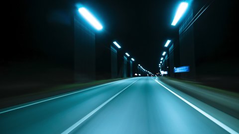 Motion timelapse of a speedy night drive near a big city. View from the car window to the road with light trails from vehicles and street lights. Hyperlapse Road Trip Dashcam POV
