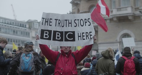 London, UK - 01 22 2022: A man protester holding a banner, ‘The Truth Stops BBC Here’, at Portland Place, in preparation for the ‘World Wide Rally For Freedom’, during pandemic.