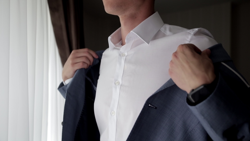 Close up view of man adjusts his suit. Business man put suit on during morning routine at home, preparing to go to work | Shutterstock HD Video #1086054116