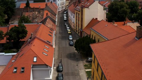 Vehicles Parked In The Roadside Of Streets Between Red Roofed Buildings In Pecs, Hungary. - aerial
