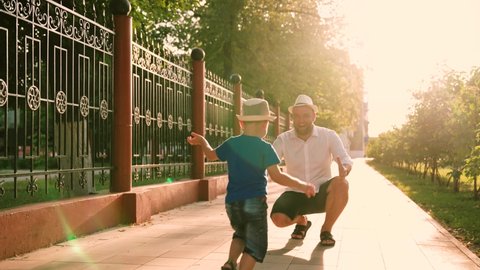 Carefree childhood, joyful run of baby to his father. Happy family embrace. Child, son runs to his father and hugs. Family in park in summer. Small child has fun playing outdoors in summer with parent