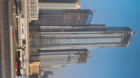 Timelapse. vertical video. Skyscraper construction in Dubai. The flow of cars on the highway. Construction crane in the process of construction.