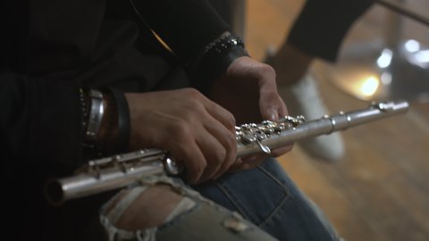 Male hands hold a flute. The musician plays in the orchestra. Classical music in live performance