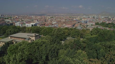 Aerial view of Konya city, drone descends from the city towards the trees of Alaeddin Hill