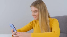 Beautiful young blonde woman using modern mobile phone for communication. Pretty white female browsing internet news feed on smartphone. Young adult person communicating on social media application