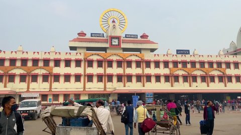Exterior front view of Varanasi Railway Station building with moving passengers and vehicles: Varanasi,  Uttar Pradesh, India - November 20 2021