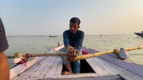 Young man sailing boat in the Banaras river during sunset: Varanasi, Uttar Pradesh, India - November 18 2021