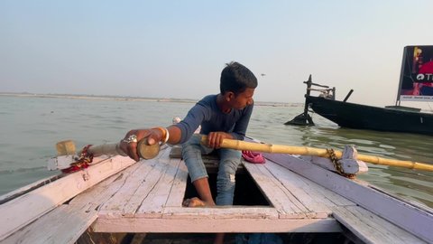 Young man sailing boat in the Banaras river during sunset: Varanasi, Uttar Pradesh, India - November 18 2021