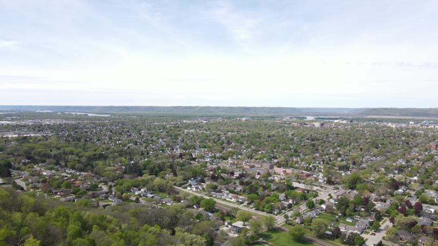 Mesmerizing aerial view of rural community in a valley in Wisconsin with a view of the Mississippi River and mountains in the distance. Hazy blue sky. Golf course tucked in base of mountain.