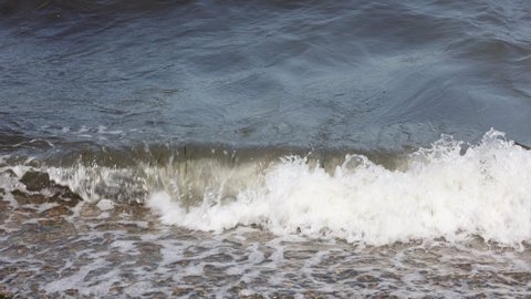 Waves Wash Over A Pebble Beach With Small Stones And Rocks. Sea Surf On A Summer Day On The Beach. The Waves Of The Sea In Focus