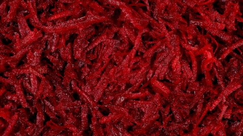 Close up top view flat lay 4k stock video of texture of raw uncooked fresh juicy grated beetroot vegetable. Red organic veggie abstract background