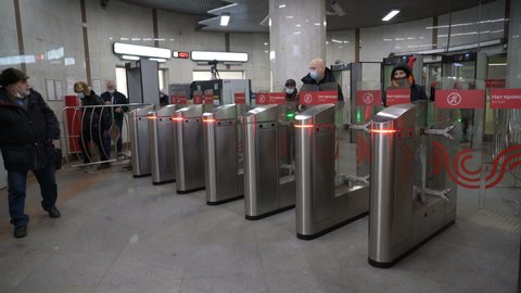 MOSCOW, RUSSIA - Jan 27, 2022: red light on subway turnstiles. hurrying passengers bypass disabled turnstiles in subway from side through fence. Passenger fare payment system in process of rebooting