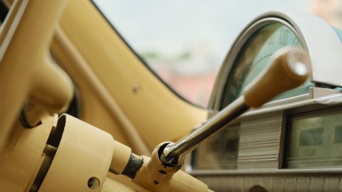 close up view of gear shift of manual transmission on beige colored steering wheel. Shifting into first gear on retro vintage old car with approved paint on metal.