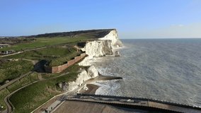 The white chalk cliffs at Seaford Head in East Sussex with the Golf Course in the background running along the top of the cliffs. Aerial Footage.