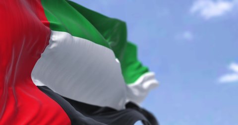 Detail of the national flag of United Arab Emirates waving in the wind on a clear day. Democracy and politics. Patriotism. Selective focus. Seamless Slow motion