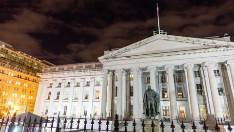 Washington, DC - USA - January 23 2022: The north entrance of the U.S. Department of the Treasury Building and Albert Gallatin statue seen in a nighttime time-lapse that pans from left to right.