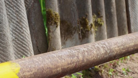 A man's hand paints a rusty pipe with a brush with yellow paint neatly. Rust prevention concept, metal corrosion protection. Work on the maintenance and repair of the water supply system. UHD 4K.