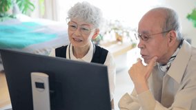 Asian elderly couple watching a monitor of PC.