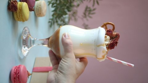 Woman hand put on table milkshake with caramel syrup, popcorn and brezel waffles decorating dry rose