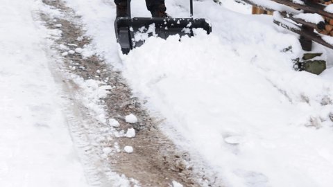 Close-up of snow removal. A man with a large cage shovel cleans snow outside