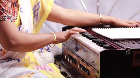 An Indian woman in saree playing harmonium on white background with selective focus