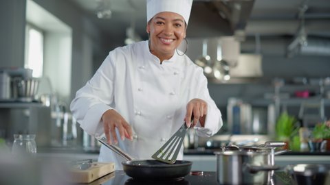 Restaurant Kitchen: Black Female Chef Fries Organic Patty on a Pan, Seasons it and Flips Cutlet with a Smile. Cooking Delicious and Traditional Authentic Food. Healthy gourmet Dishes. Medium Shot