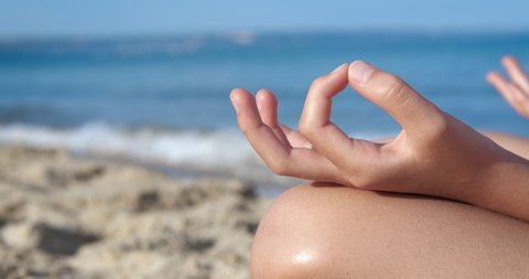 Hands in meditation position on beach. A view of hands and legs in yoga position on the beach. A concept of relax time under the morning sun.