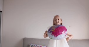 Indoor shot of pretty joyful cute adorable girl kid celebrating eight years old birthday with bright and colorful balloons, wearing casual fashionable dress. Kid having fun. Slow motion