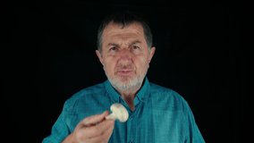 Caucasian Adult Senior Vegan man in white shirt Eating fresh champignon mushroom. High quality 4k footage in slow motion with feelings