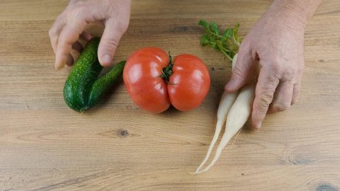 Man puts on the table ugly vegetables. Ugly big tomato, cucumber, white radish. High quality 4k footage