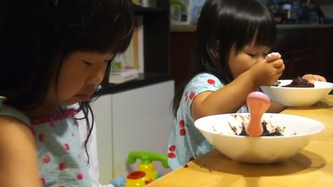two pretty asian toddler girls eating cake