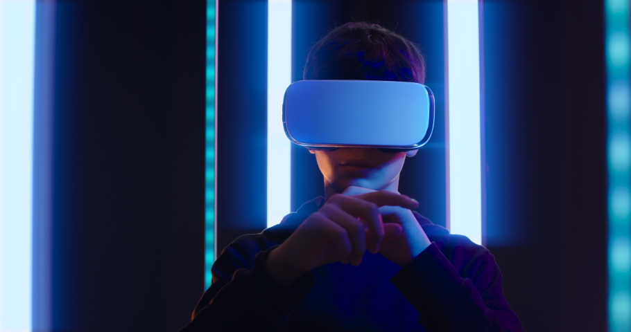 Teenager wearing VR glasses and experiencing immersive virtual reality, he is interacting with a virtual user interface | Shutterstock HD Video #1086117437