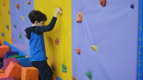 A school-age boy climbs the wall of a climbing wall.