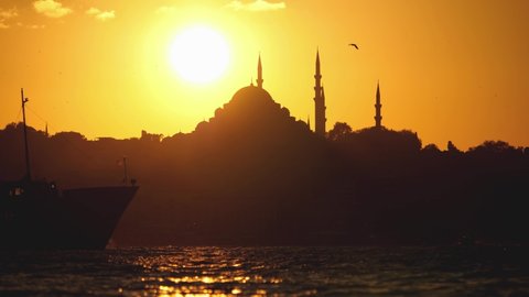A city lines passenger ferry passes as the sun sets over the Suleymaniye Mosque.