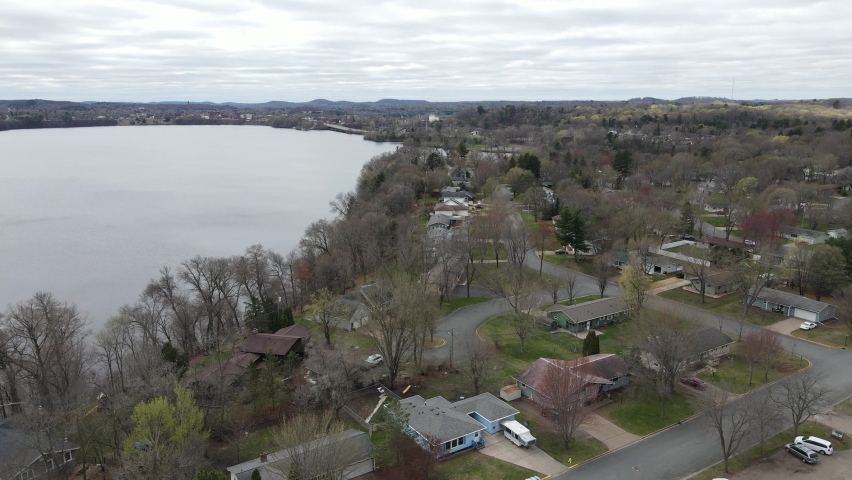 View of Menomonie Lake on a gray cloudy day.Tree line shoreline.  Residential neighborhood on the edge of the lake and sprawling city in view. Cool autumn day in Wisconsin.  