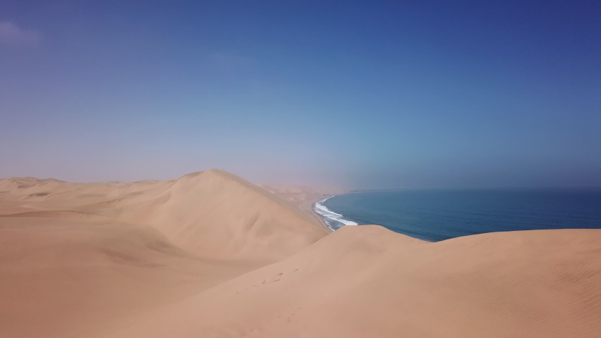 Sandwich Harbour in Namibia at the coast of the Atlantic Ocean. Sandy beach, dunes on the seashore. Summer vacations, wild desert nature in Africa. Namib-Naukluft national park.