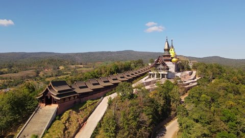 Aerial footage sliding to the right revealing the famous Wat Somdet Phu Ruea and mountains and forest around it, Ming Mueang, Loei in Thailand.
