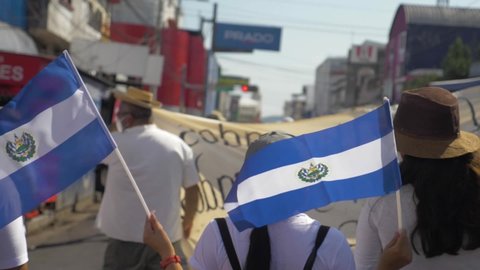 San Salvador , San Salvador , El Salvador - 01 16 2022: Salvadorans walk with the national flag during a peaceful protest in the city streets against current president Nayib Bukele