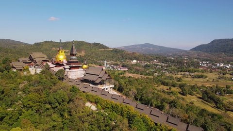 Aerial footage sliding to the left revealing the village of Ming Mueang and then Wat Somdet Phu Ruea, Ming Mueang, Loei in Thailand.