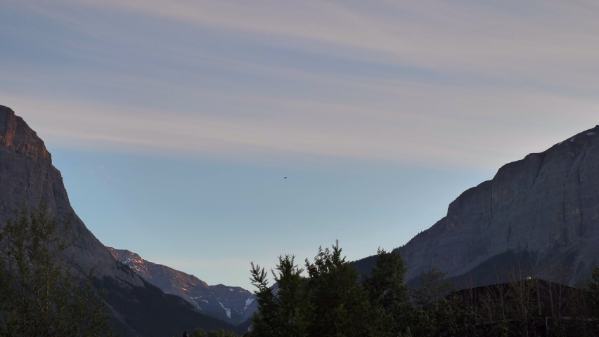 Person Hang Gliding Over Valley In Between Mountain Peaks in the Canadian Rockies, Alberta, Canada