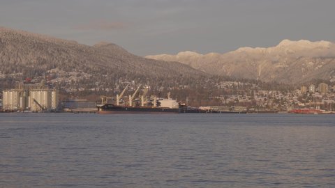 Vancouver, British Columbia, Canada - December 31, 2021: Panoramic View of Modern City, Industrial Site, Vancouver Harbour and Mountain Landscape. Winter Sunset. Taken from Stanley Park, Downtown.
