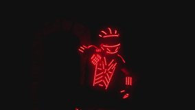 Man dressed in led illuminated costume with colorful lights dancing and moving inside dark interior or club . Dancer guy wearing clothing with neon lights on his body and dances . Shot on ARRI camera