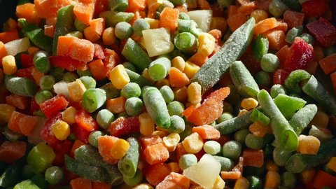 Vegetable stew. A dish of frozen vegetables is cooked in a frying pan. Asparagus, corn, pepper, peas.